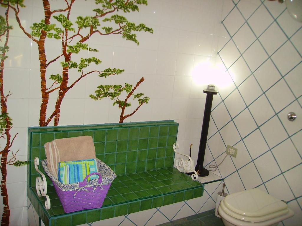 Baño de azulejos verdes con aseo y árboles en L'Antica Cantina, en Usini
