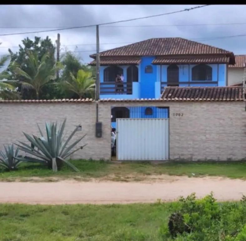 a blue house with a white gate in a yard at Casa de praia Silva Bráz in Serra