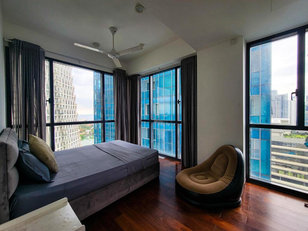 a bedroom with large windows and a bed and a chair at Lake and Sea view apartment at Capitol twinpeak in Colombo
