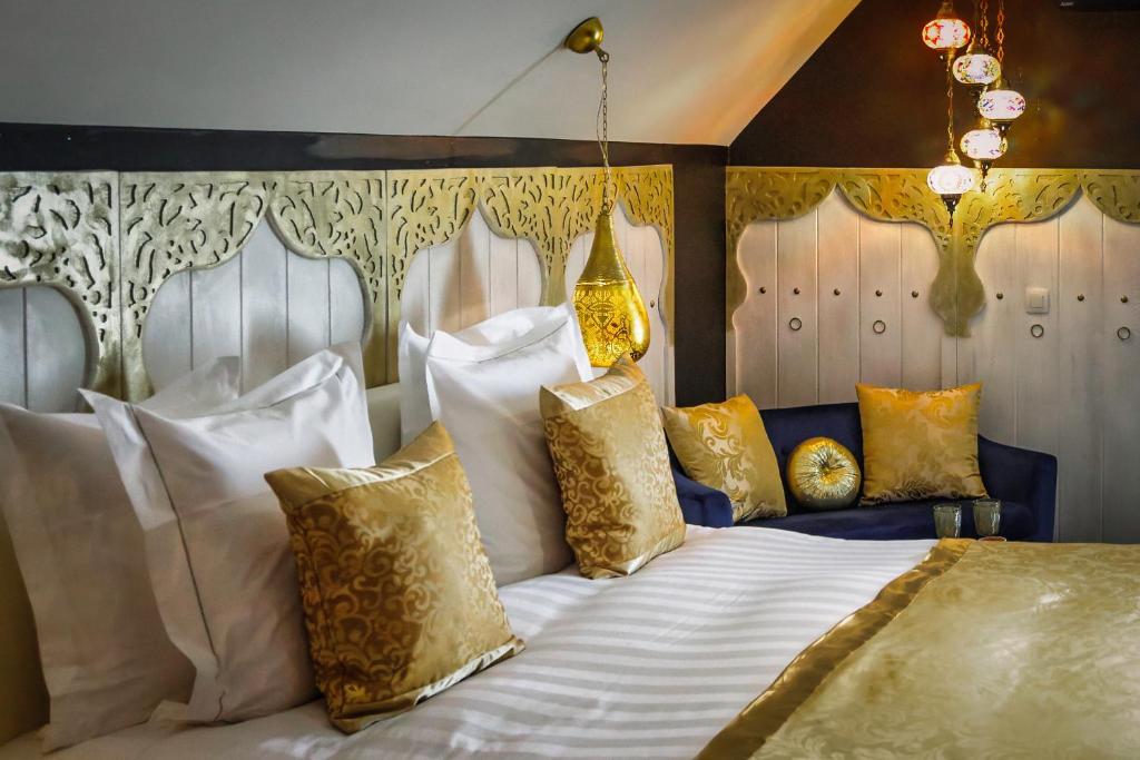 een slaapkamer met een bed met witte en gouden kussens bij B&B 1001 nacht in Zonhoven