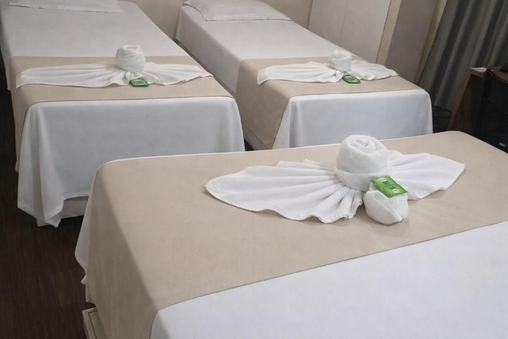 un gruppo di quattro letti con asciugamani bianchi sopra di Cristal park flats a Cristalina