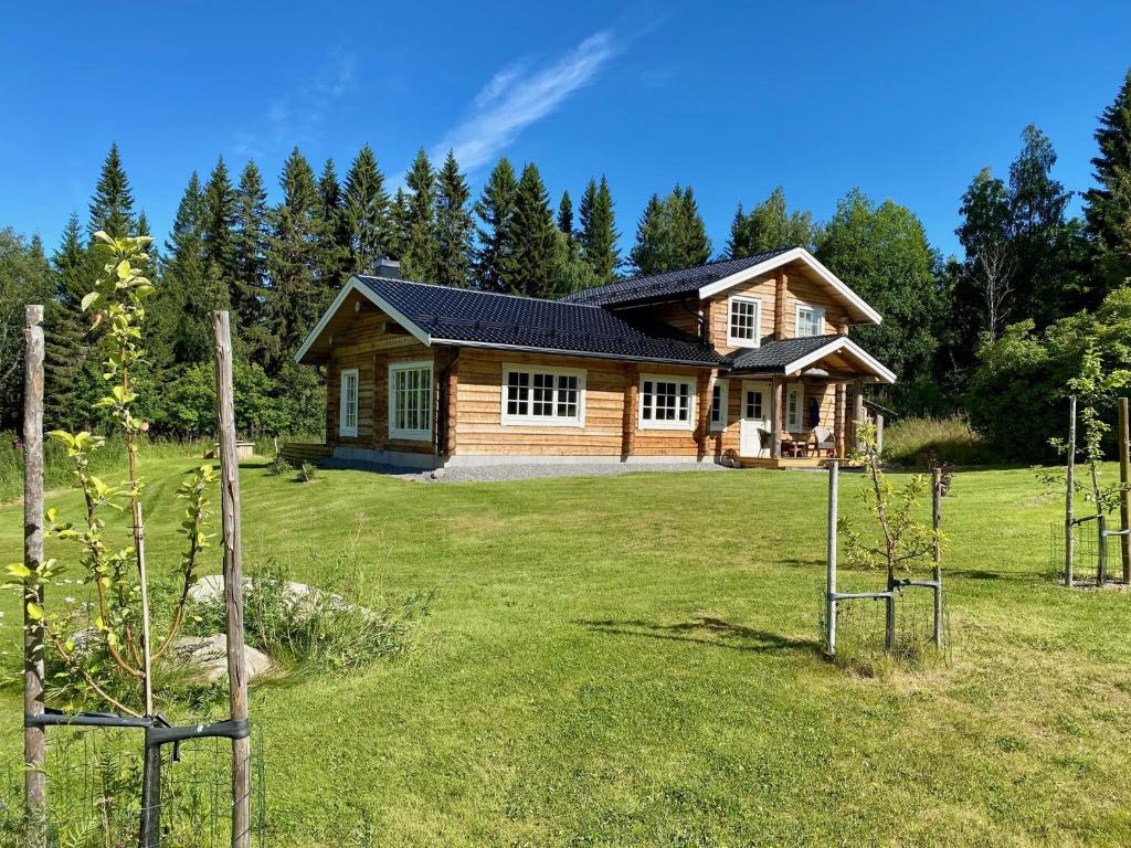 a log house in a field with a yard at The Moose Lodge Swedish Nature Retreat in Bräcke
