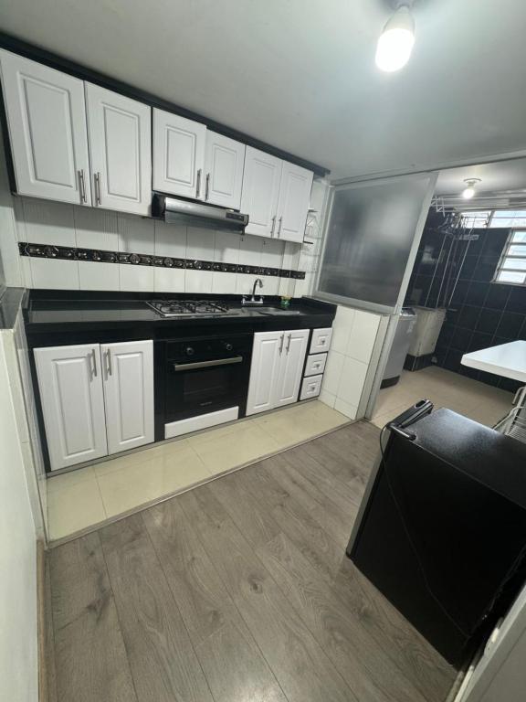 a kitchen with white cabinets and a black stove at Espectacular Apartamento 1-6 huéspedes in Tunja