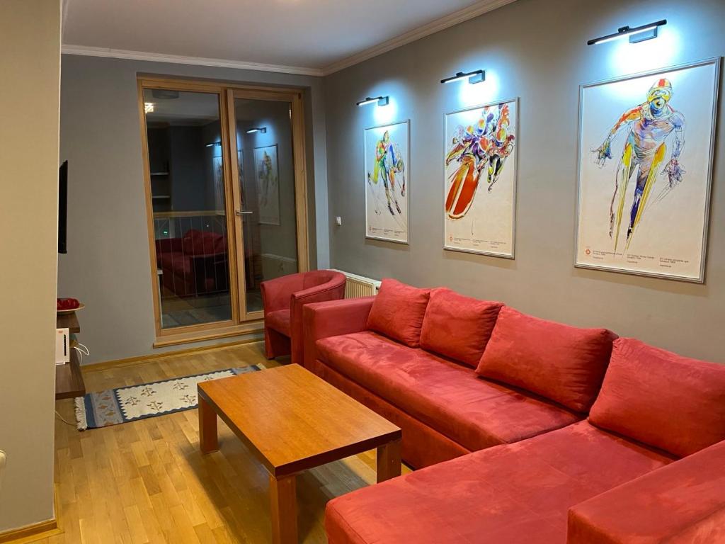 a living room with a red couch and a table at Bjelašnica Babin do Apartman in SJJ