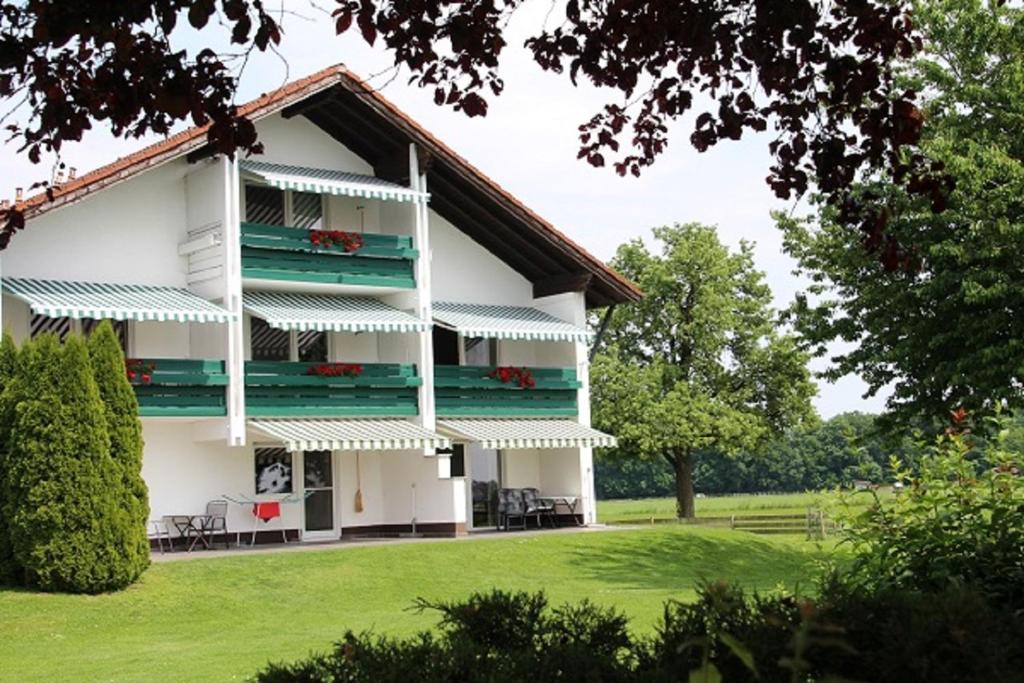 ein weißes Gebäude mit grünen Balkonen auf einem Rasen in der Unterkunft Erwachsenen Aparthotel DER WIESERHOF Wunderschöne Einzellage in Bad Füssing