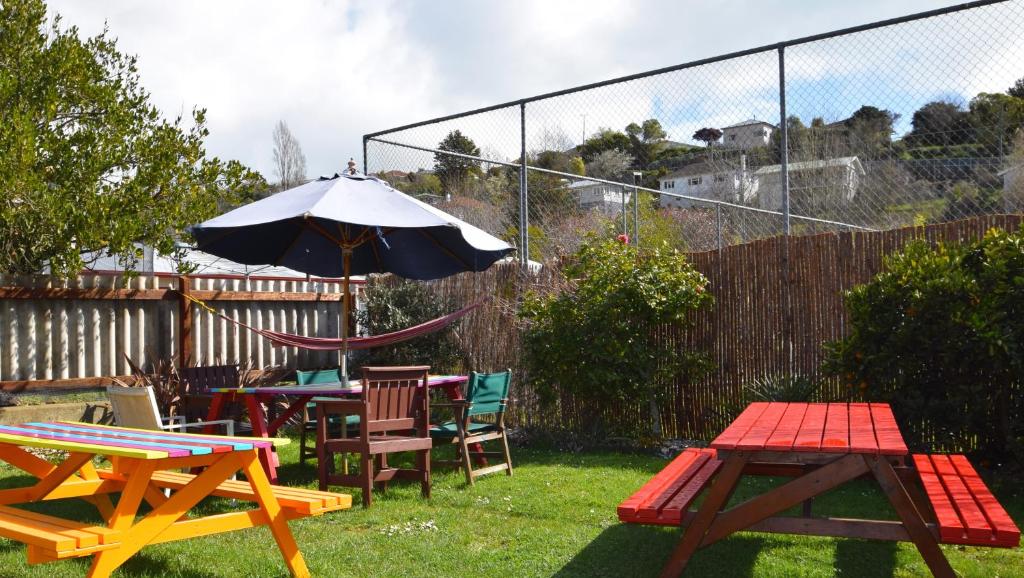 a patio with tables and chairs and an umbrella at The Bug Backpackers in Nelson