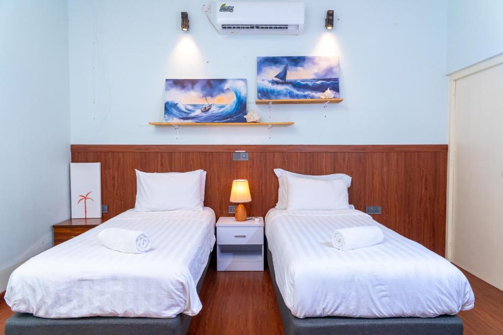 zwei Betten in einem Zimmer mit weißer Bettwäsche in der Unterkunft Samaik Cottage in Thulusdhoo