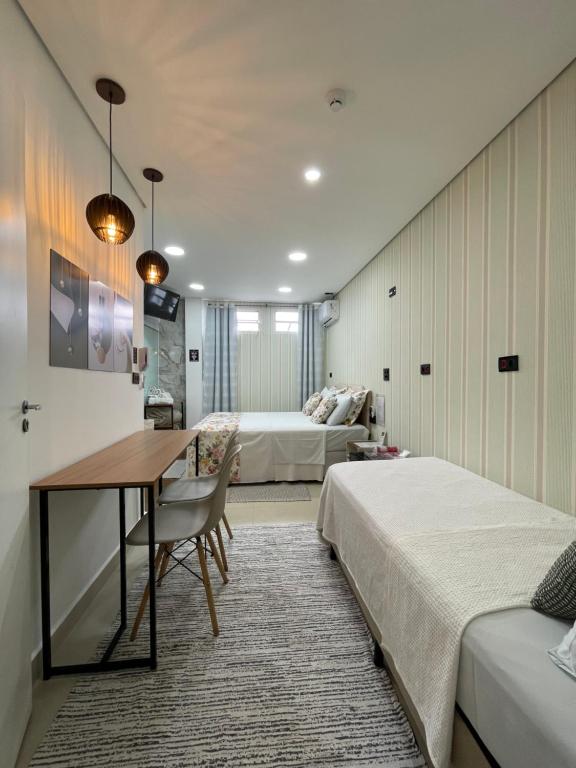 a bedroom with two beds and a table and a desk at Green It Motel & Hotel in Bragança Paulista