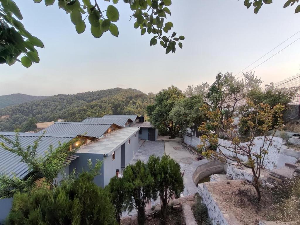 una vista de un edificio blanco con árboles en el primer plano en The woodpecker nest by lake & woods, en Rāmgarh