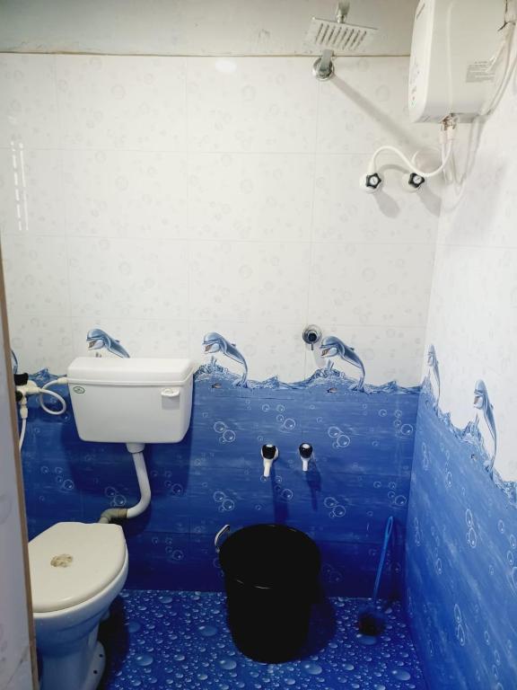 a blue bathroom with a toilet and water faucet at Gokarna Royal Cottage in Gokarna