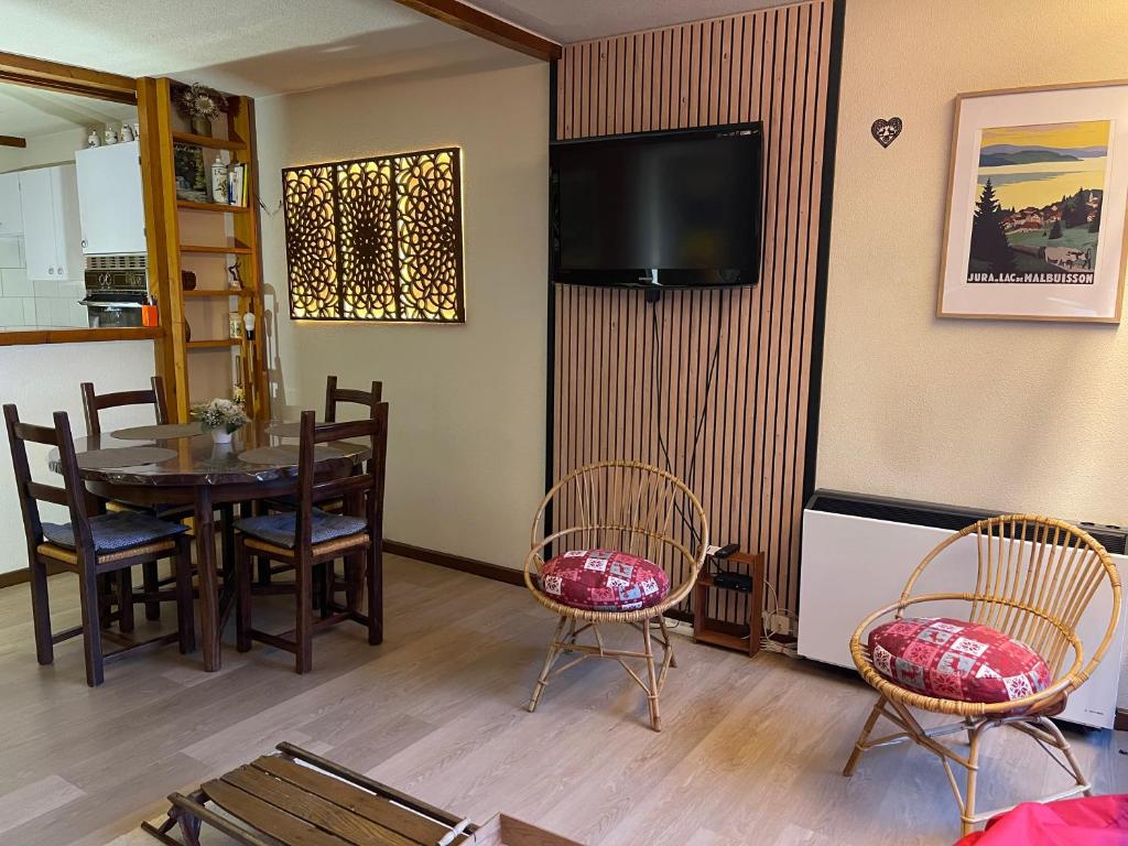 ein Esszimmer mit Tisch und Stühlen und einem Fernseher in der Unterkunft Vaste appartement de montagne in Métabief