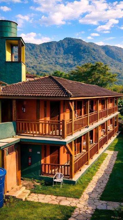 a large house with a mountain in the background at Pousada Nusa Dua Maresias in Maresias