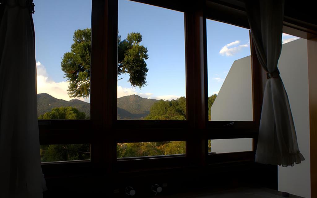 a window with a view of a mountain view at Chalés Colline Verte in Monte Verde