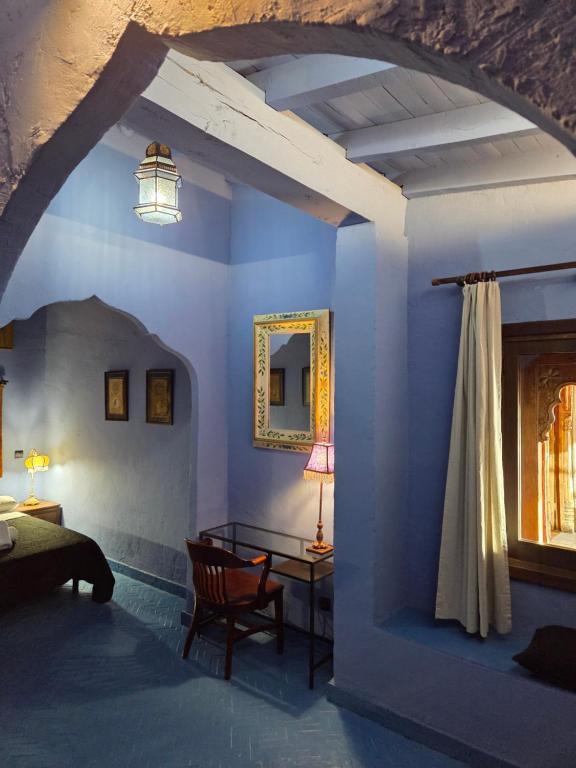 ein Schlafzimmer mit blauen Wänden, einem Bett und einem Tisch in der Unterkunft La PuertaMora in Orgaz