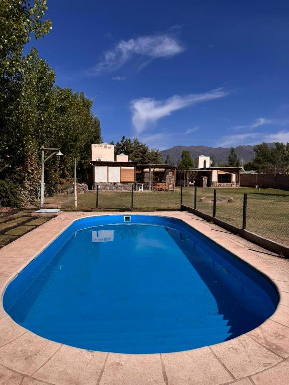 a large blue swimming pool in a yard at Cabañas del Pasaje in Las Compuertas