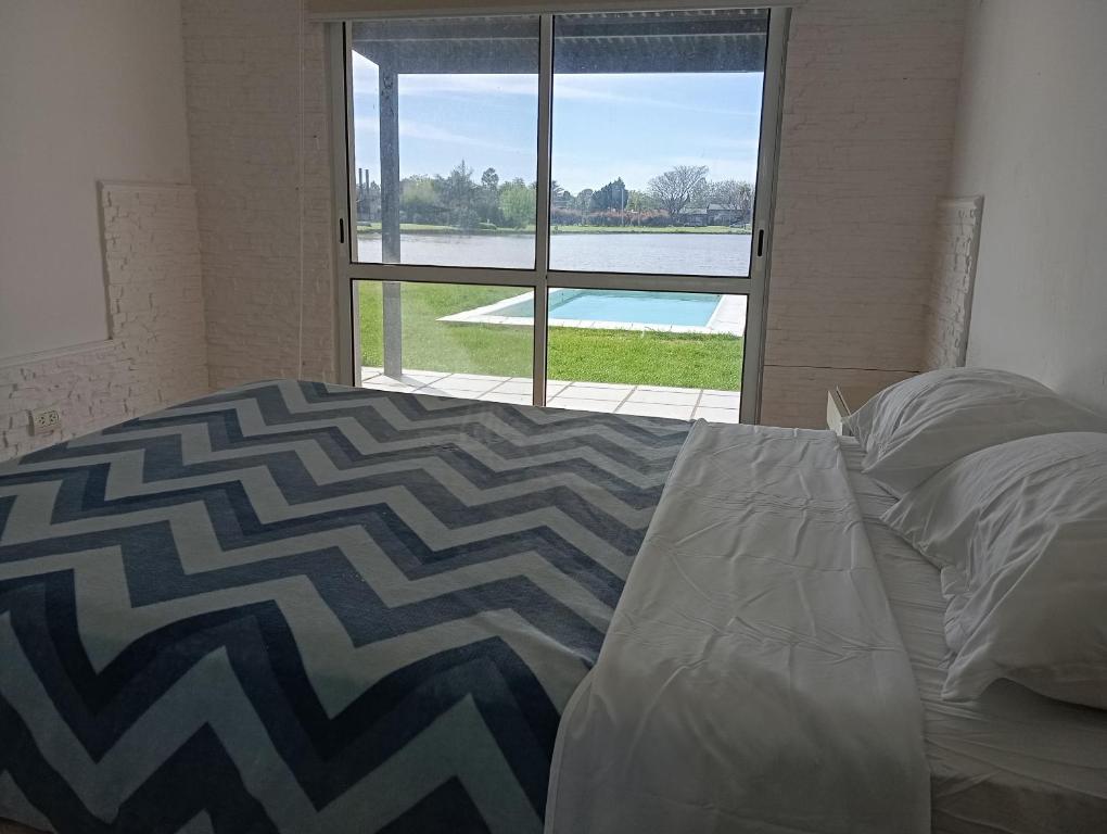 ein Schlafzimmer mit einem Bett und einem großen Fenster in der Unterkunft Casa solares del carcaraña in Maciel