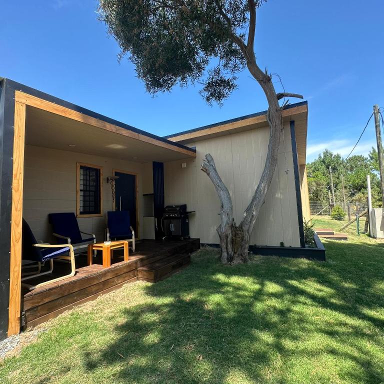 a house with a porch with two chairs and a tree at Posada Bliss in Punta del Este