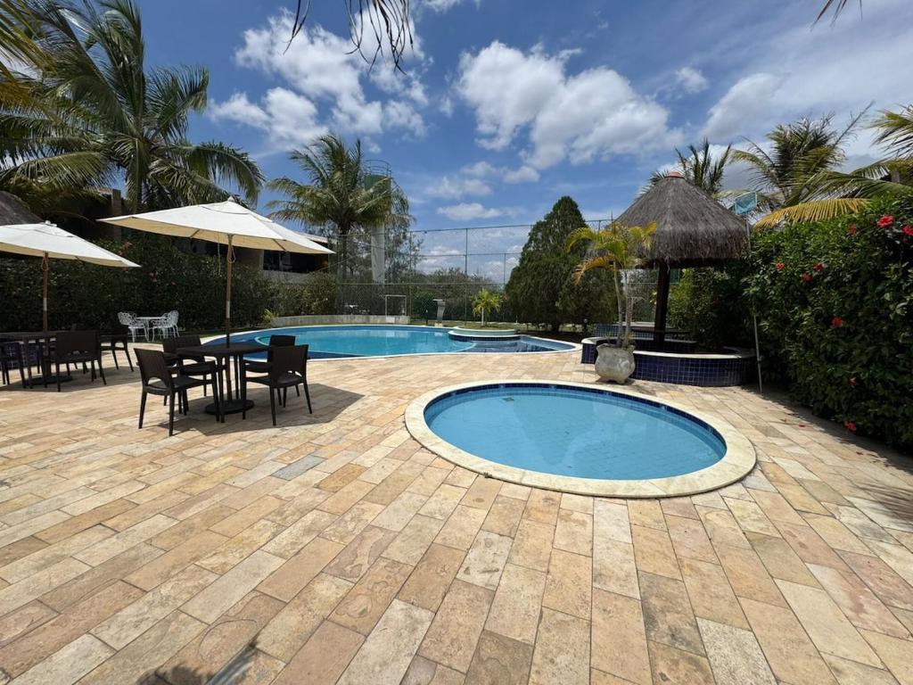 eine Terrasse mit einem Pool, einem Tisch und Stühlen in der Unterkunft Vila Bella Residence in Gravatá