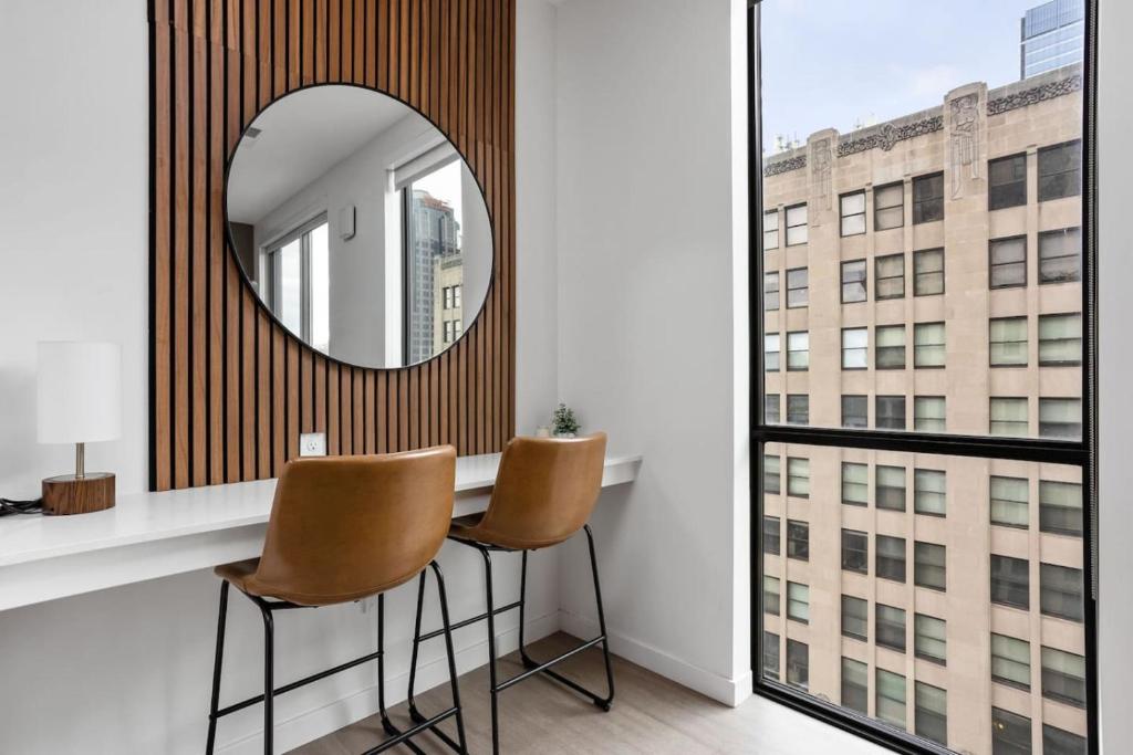 een spiegel aan de muur boven een tafel met twee stoelen bij Premium Downtown High-Rise Condo with Pool, Parking, Gym in Indianapolis