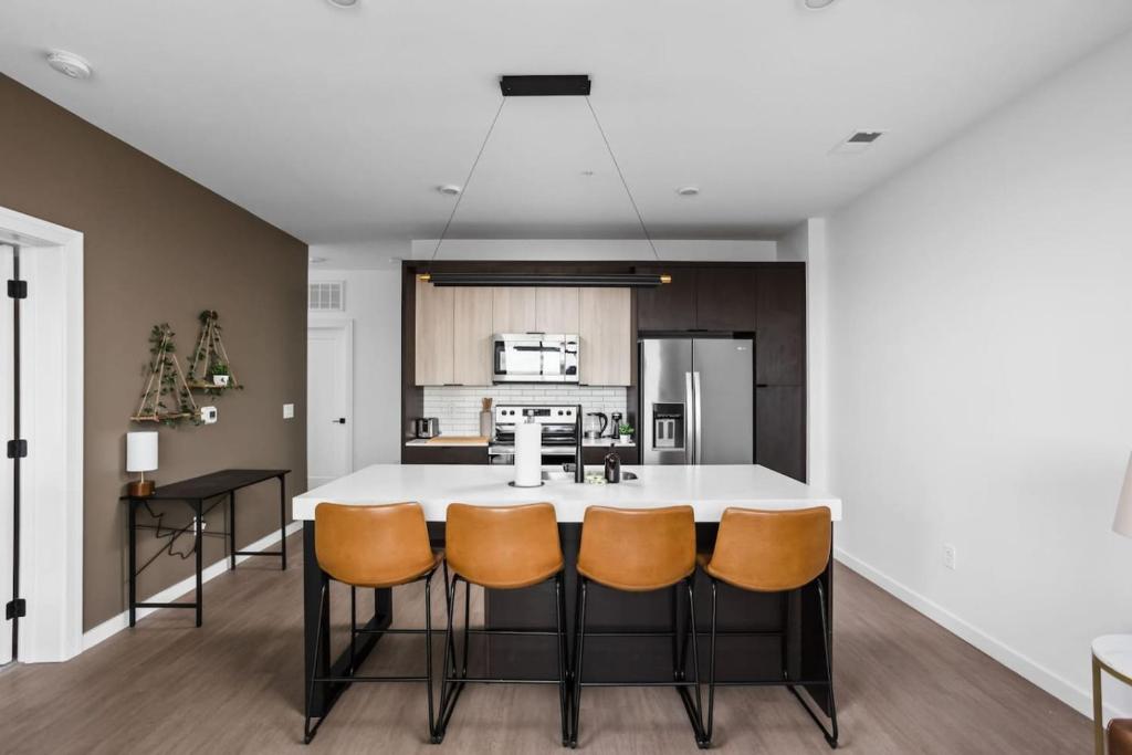eine Küche mit einer großen weißen Insel mit orangefarbenen Stühlen in der Unterkunft Downtown Indy Luxury Stay in Indianapolis