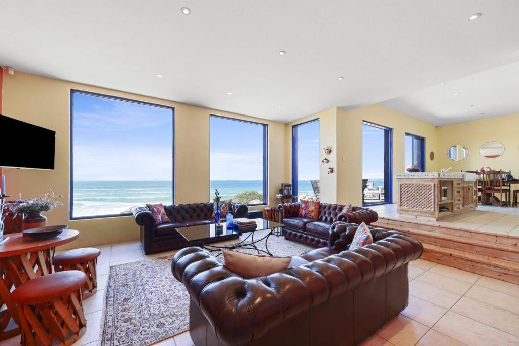 a living room with leather furniture and large windows at Casita Alegre - Clifftop Stay Above Knight Beach in Port Elliot