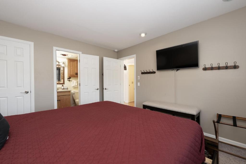 a bedroom with a red bed and a flat screen tv at Comfortable Mountain Getaway near Winter Park in Fraser