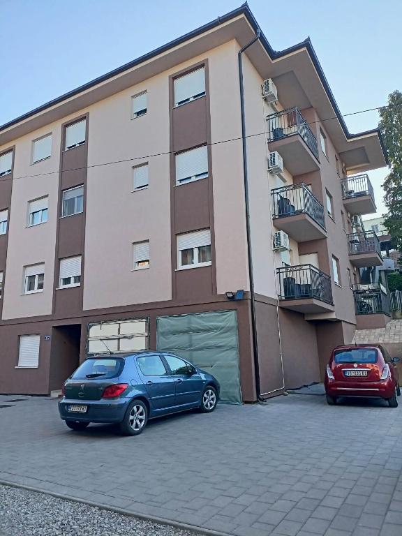 two cars parked in a parking lot in front of a building at studio apartman in Vrnjci