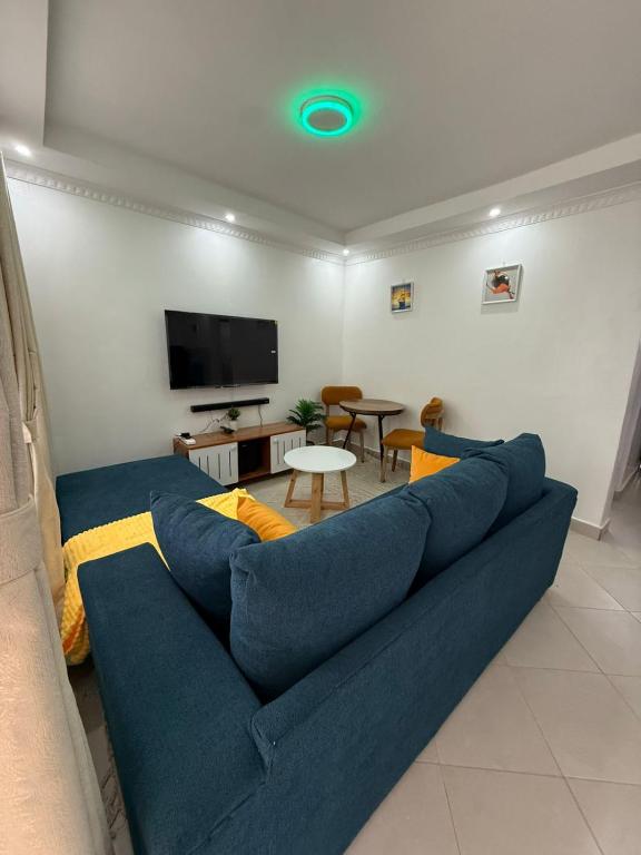 a living room with a blue couch and a tv at NikLan Homes in Naivasha
