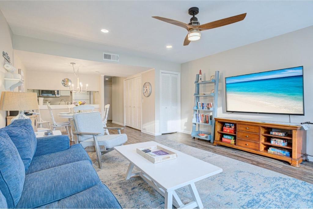 a living room with a blue couch and a flat screen tv at Pool - Ocean View - Walk to Beach - Captain Villa in Fripp Island