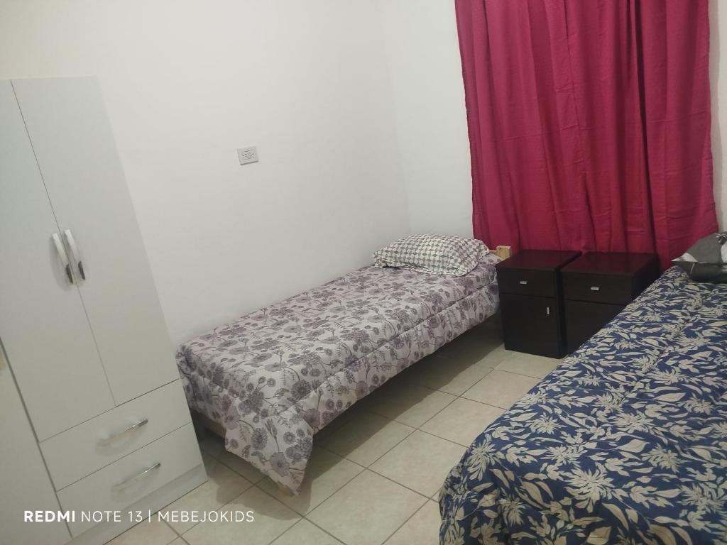 una piccola camera da letto con due letti e tende rosse di Departamento en San Luis, Capital a San Luis
