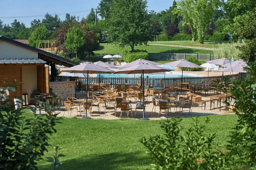 een groep tafels en stoelen met parasols bij Camping 5 étoiles - Piscine - ccbefbi in Gourdon-en-quercy