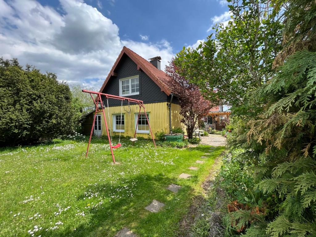 a house with a yard with a swing at Ferienwohnung Dorle in Benneckenstein