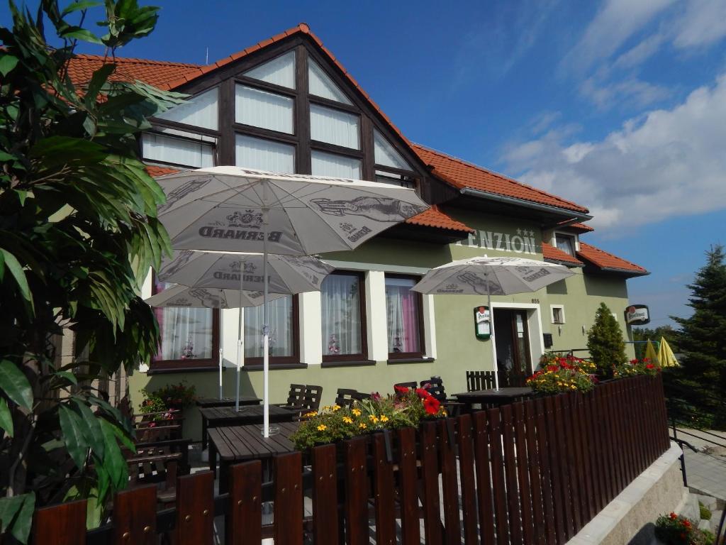 a house with tables and umbrellas in front of it at Penzion U Kašných in Mníšek pod Brdy
