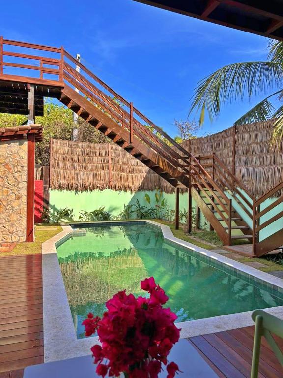 a wooden bridge over a swimming pool with pink flowers at Pousada Jurará e Vila Jurará in Atins