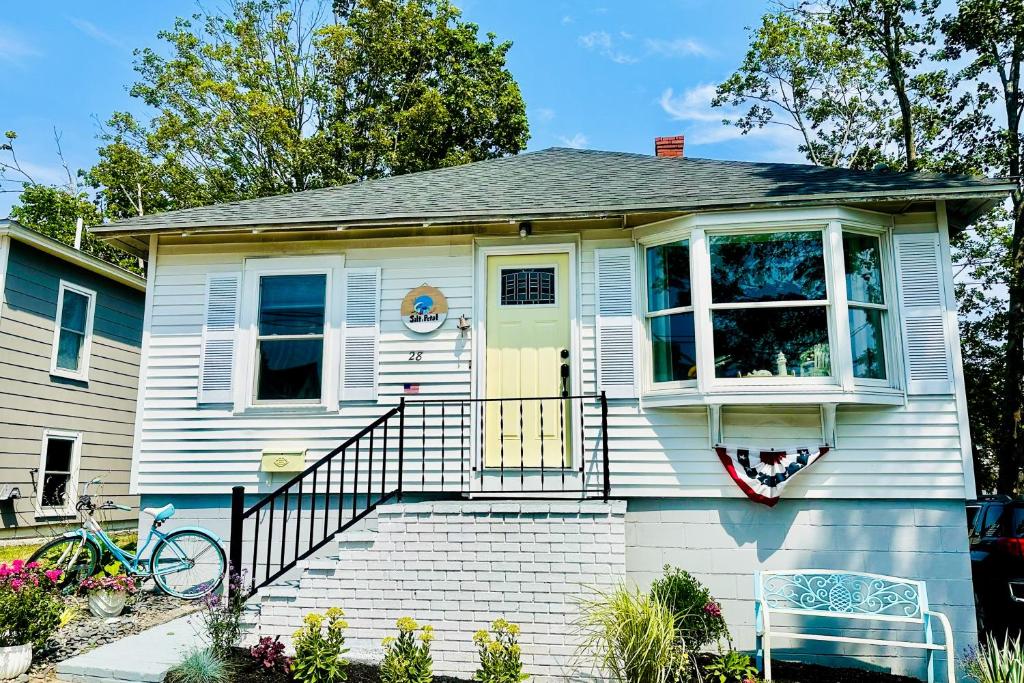 a small white house with a yellow door and stairs at Salt & Petal in Old Orchard Beach