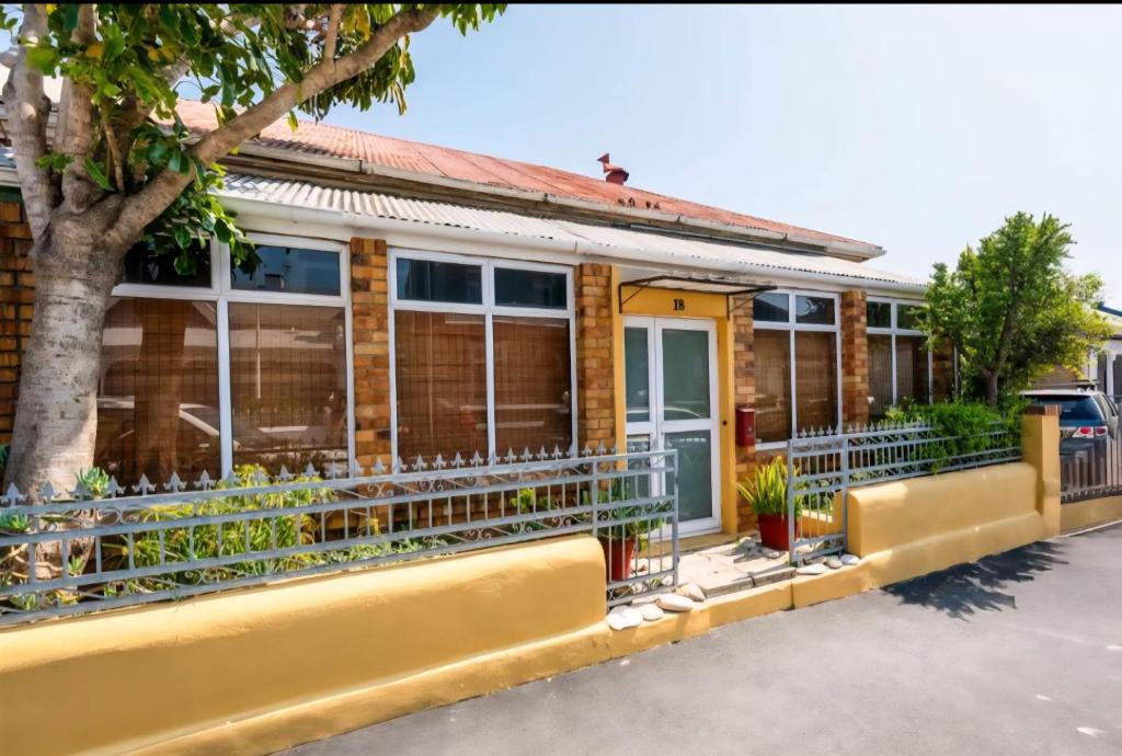 een geel huis met een boom ervoor bij Imany house in Kaapstad