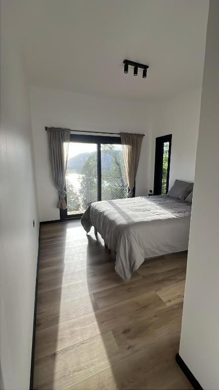 ein Schlafzimmer mit einem Bett und einem großen Fenster in der Unterkunft Increíble casa con vista al lago in Licán Ray