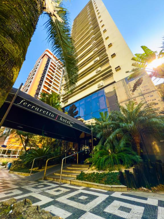 a building with palm trees in front of it at Ferraretto Guarujá Hotel & Spa in Guarujá