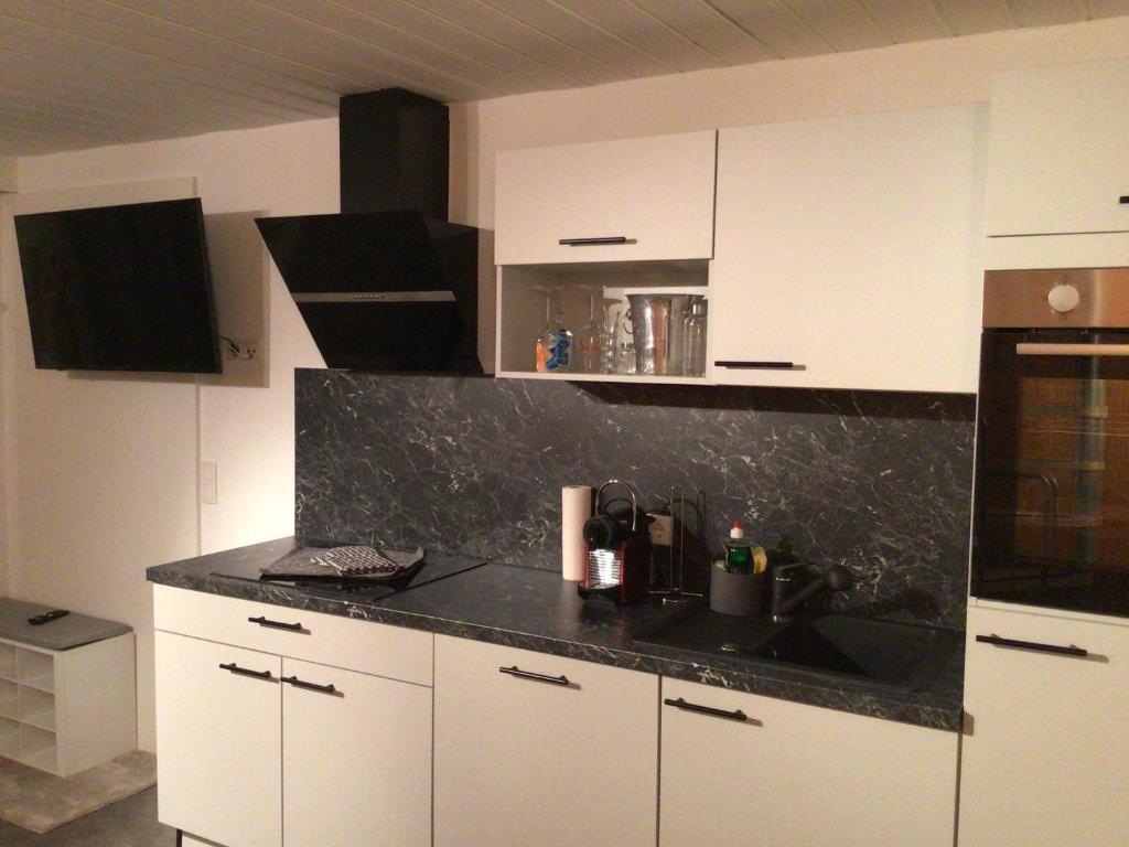 a kitchen with white cabinets and a black counter top at Ferienwohnung Bergheimat in Wenns