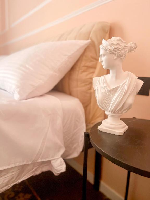 a statue of a woman sitting on a table next to a bed at Flame B&B in Catania