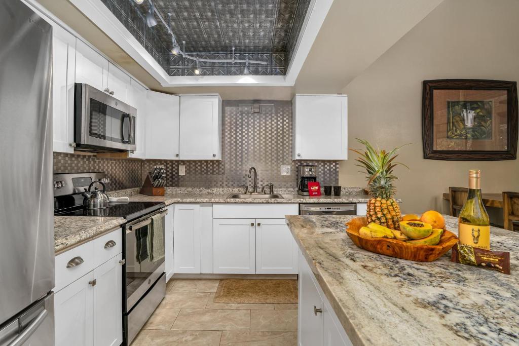 eine Küche mit weißen Schränken und einer Obstschale auf der Theke in der Unterkunft (P9B) 1Br with Loft Princeville Retreat, Pool, AC, Wifi in Puupehu