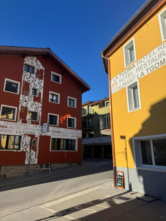 a yellow and red building next to a red building at La Tgoma - Hotel & Restaurant in Lenz