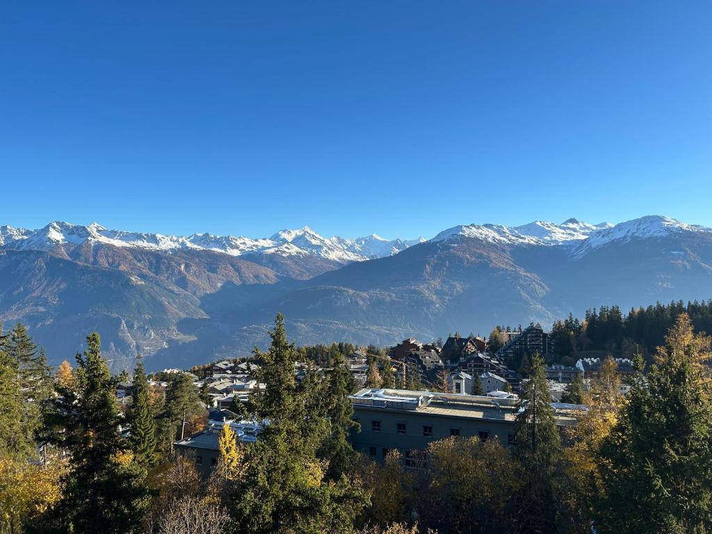 a city with snow covered mountains in the background at Sorecrans in Crans-Montana