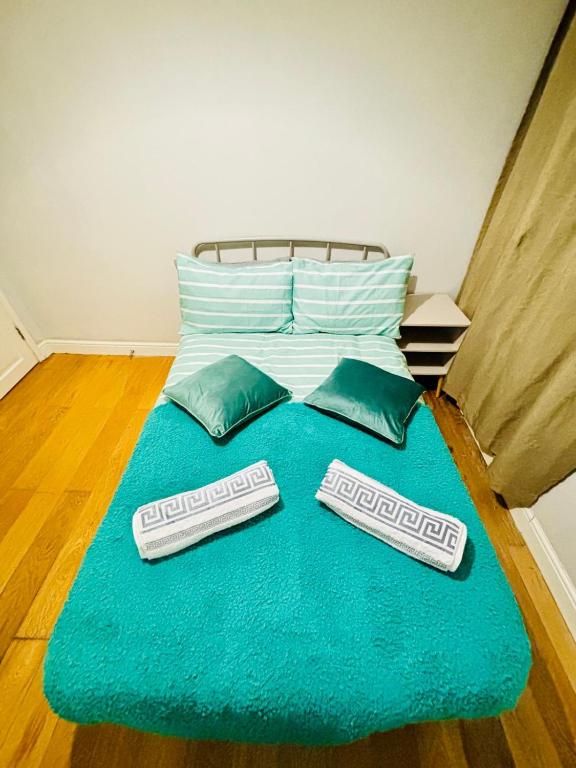 a bed with two pillows and a blue blanket at Emerald Room - shared bathroom in Ponders End