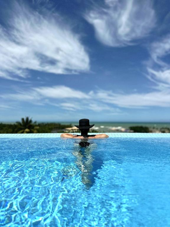 a person in a hat sitting in a swimming pool at Bela Vista Hotel Boutique in Caraíva