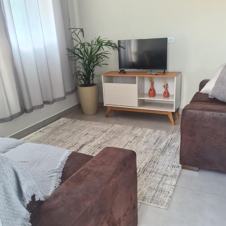 a living room with a tv and a couch at Casa 1 Montebelle in Porangaba