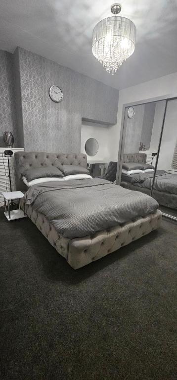 een slaapkamer met een groot bed en een kroonluchter bij Comfy 2 Bedroom House near City Centre and Uclan in Preston