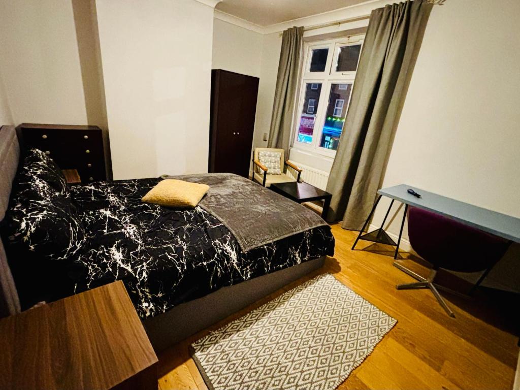 een slaapkamer met een bed, een bureau en een raam bij Midnight Horizon in Ponders End