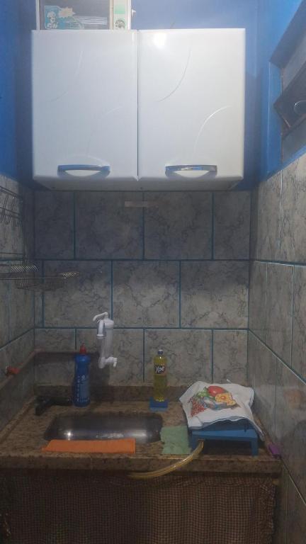 a kitchen counter with a sink and white cabinets at Panga Loft in Abraão