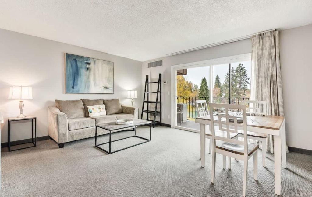 een woonkamer met een bank en een tafel bij Second-floor - Riverfront Condo Near Downtown Bend in Bend